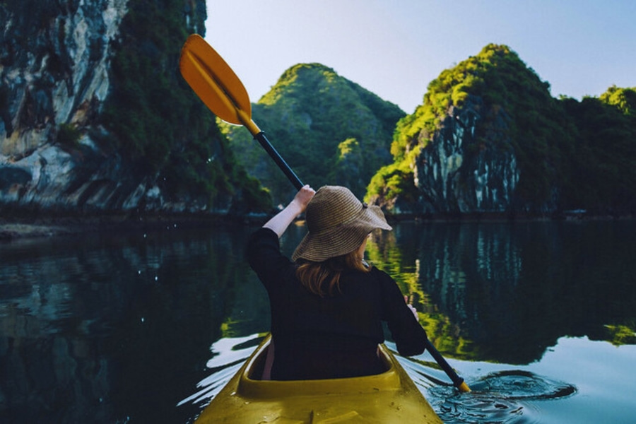 Traveler kayaking among limestone cliffs on Halong Bay Day Cruises Auasia Travel